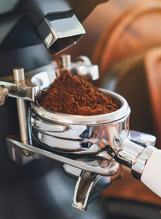 에스프레소 머신에 커피 가루가 담기는 장면으로, 커피박 재활용의 시작 과정을 상징함.