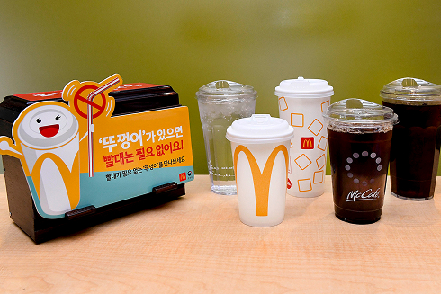 ‘뚜껑이 있으면 빨대는 필요 없어요’라는 문구와 함께 다양한 맥도날드 컵이 진열된 이미지.